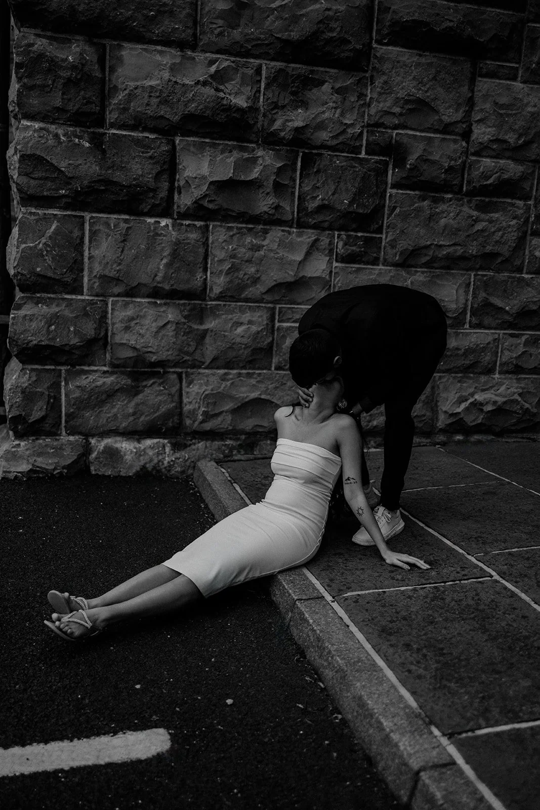 A photograph of a couple sharing a kiss on the pavement of an old city taken by wedding photographer Darius N Fernandes