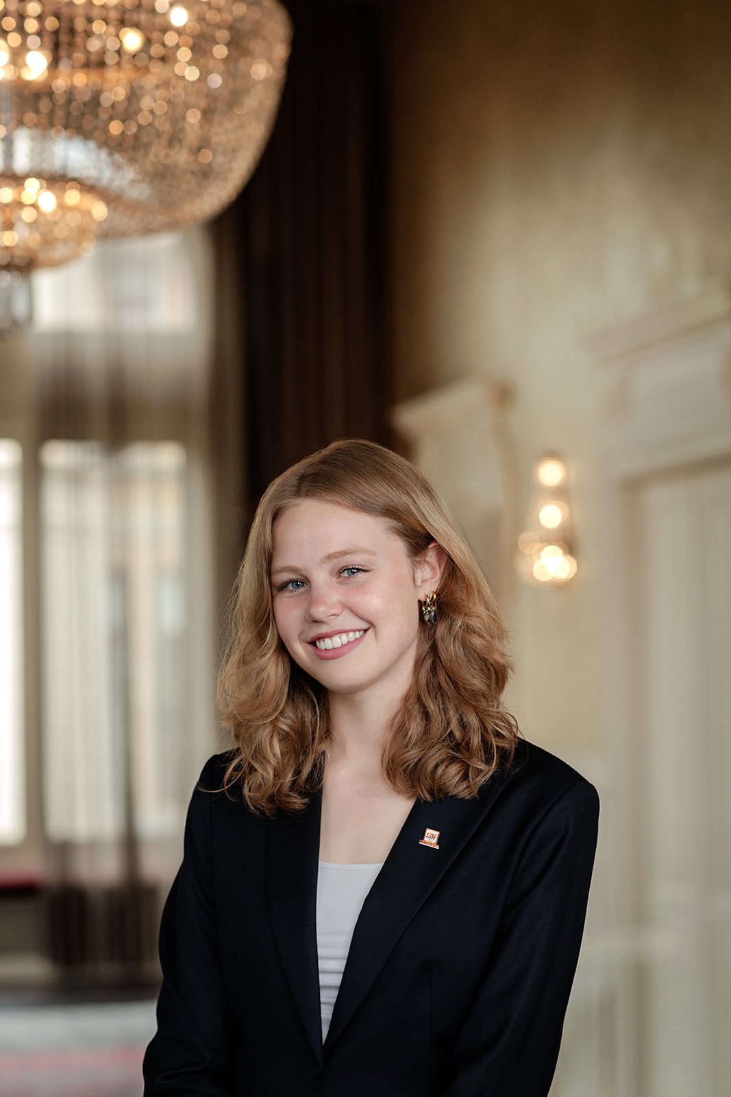 A headshot portrait photograph of a lady in blue blazer with a pin shot and a antique background by Darius N Fernandes