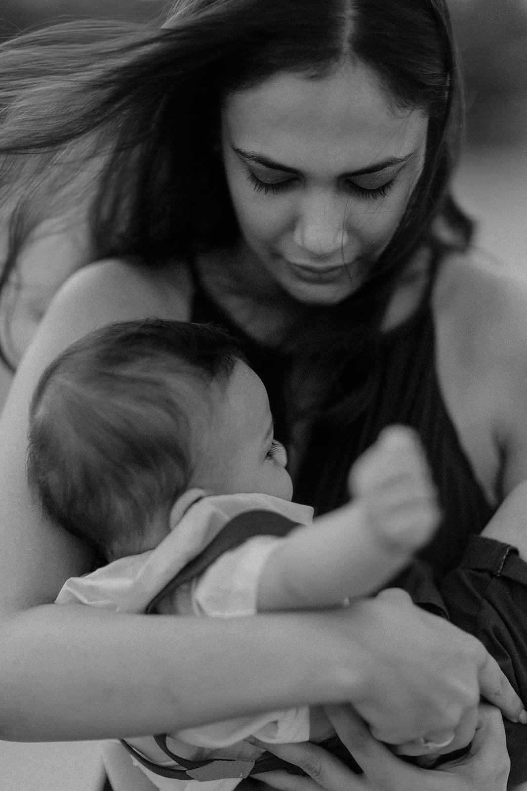 A family photograph of a lady clutching a child while the wind blows her hair as she is being photographed by Darius N Fernandes