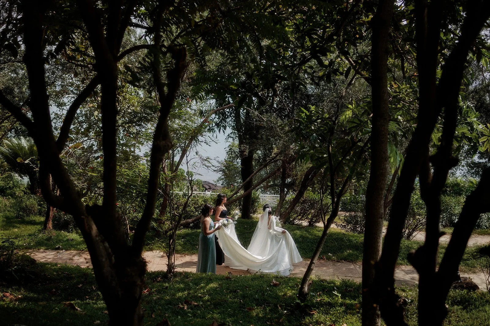 A bride walking down a forest lane looking back at her bridesmaids as she does 