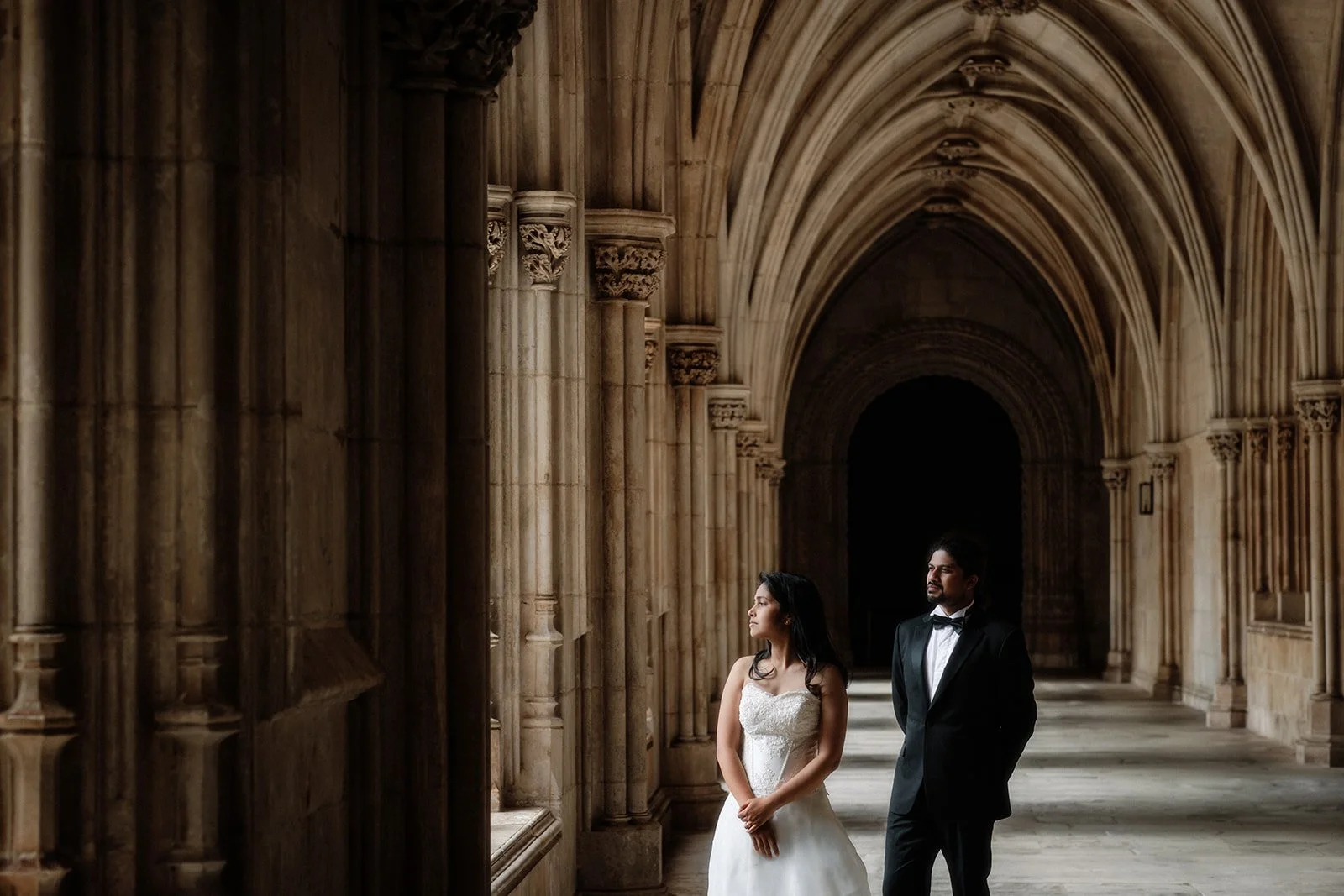 A photograph of the bride and groom standing stoically and looking out of a grand cathedral in Portugal taken by Darius N Fernandes