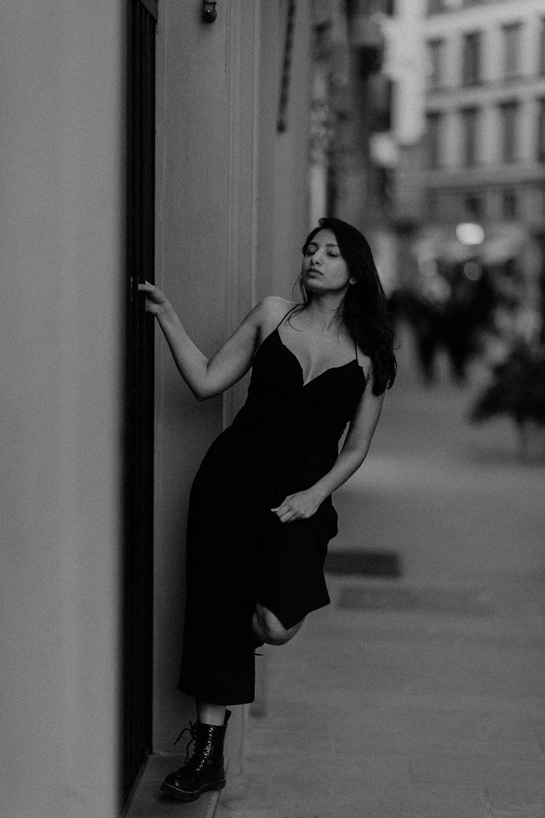 A black and white portrait taken by Darius N Fernandes where in the lady is holding and balancing herself on a pole with the beautiful streets of the Netherlands in the background