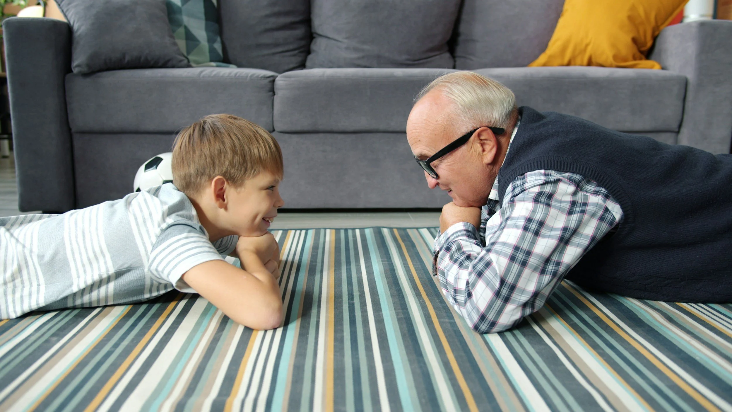 Child and older man facing against each other grinning