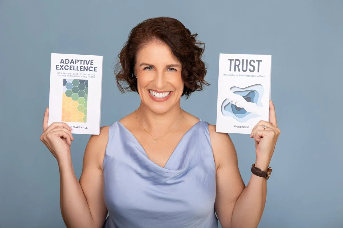 Melanie Marshall holding her books Adaptive Excellence and Trust