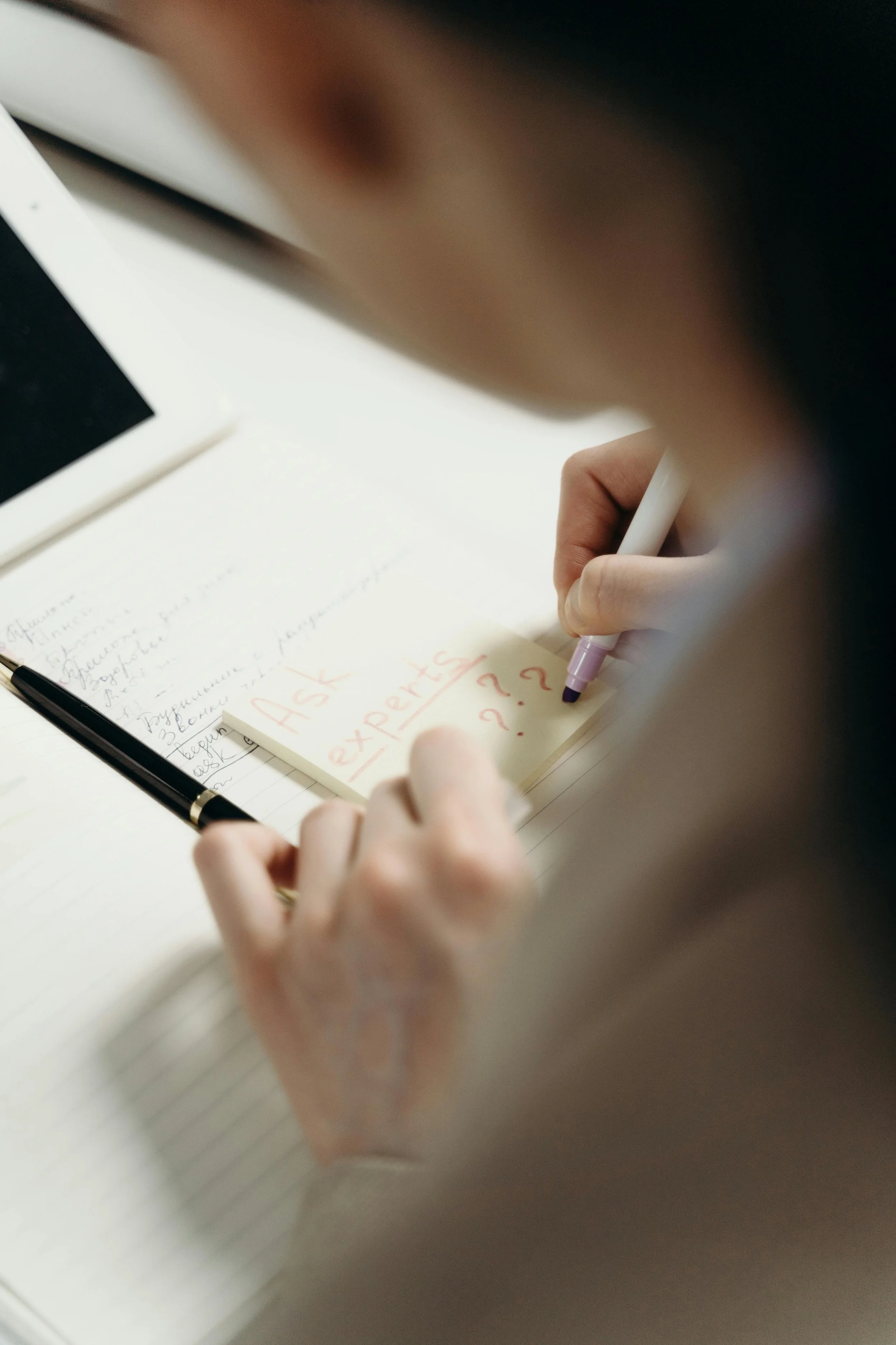 Person writing down question marks on a post it note