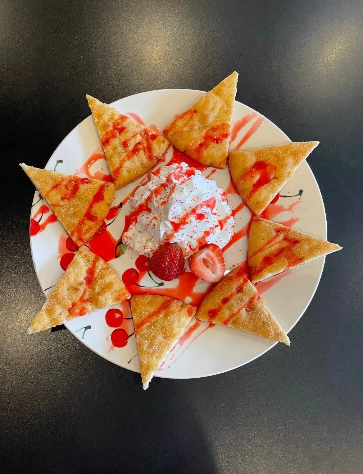 Plate of fried ice cream with strawberry sauce, whipped cream, and strawberries in the center.