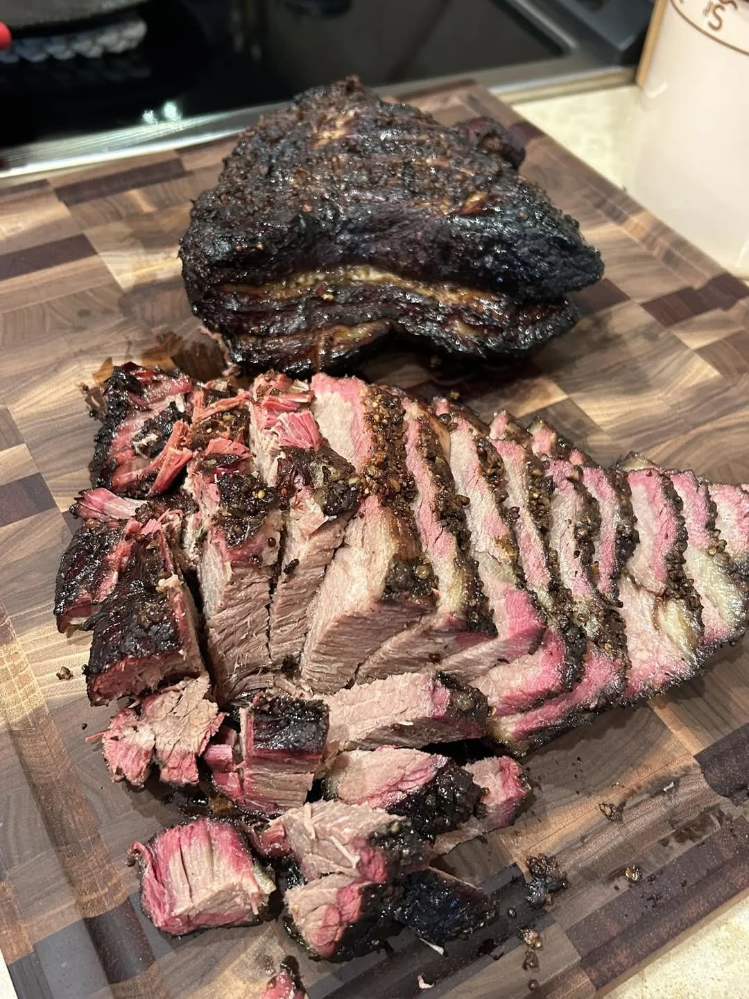 A cut of smoked brisket with a dark, crusty bark on a wooden cutting board