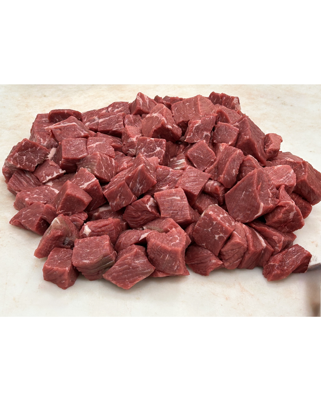 A pile of cubed raw beef steak on a light-colored surface.
