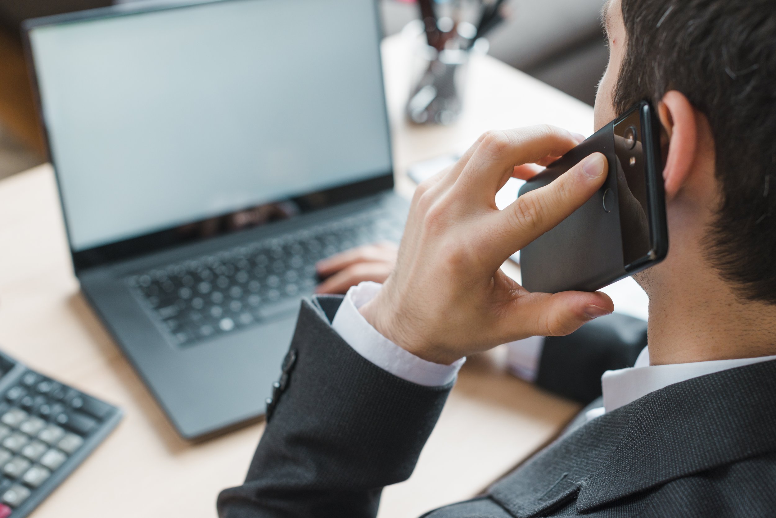 A man is talking on his cellphone at a desk