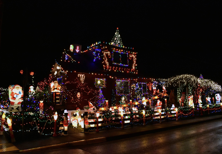 A house decorated with colorful Christmas lights, inflatable Santa Claus, snowmen, and candy canes at night.