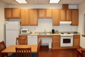 Kitchen with wooden cabinets, white appliances including a refrigerator, microwave, dishwasher, stove, and sink, and a wooden dining table with chairs.