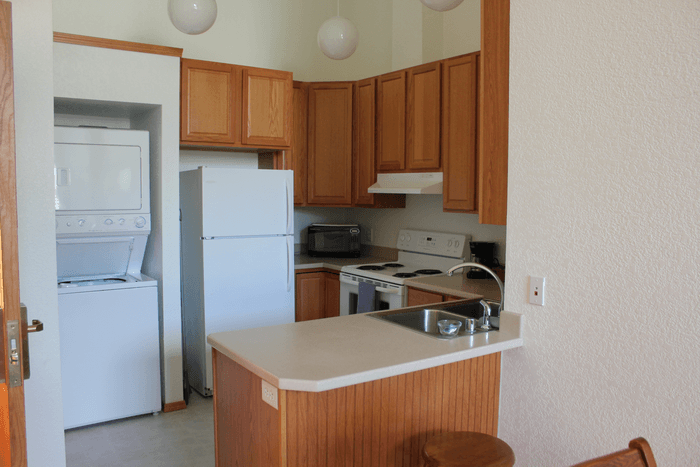 Kitchen with wooden cabinets, white appliances, and a small kitchen island with a sink.