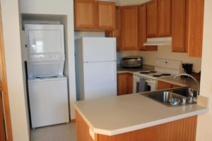 Kitchen with wooden cabinets, white refrigerator, microwave, stove, and a small kitchen island with a sink.