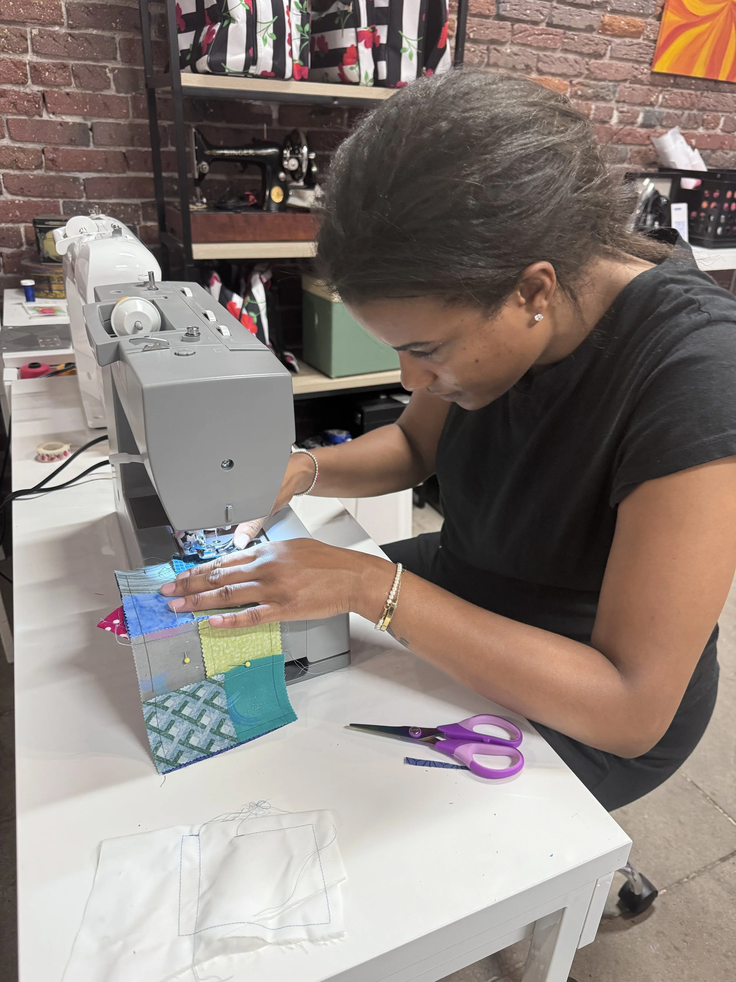Woman sewing colorful fabric pieces on a sewing machine in a craft room.