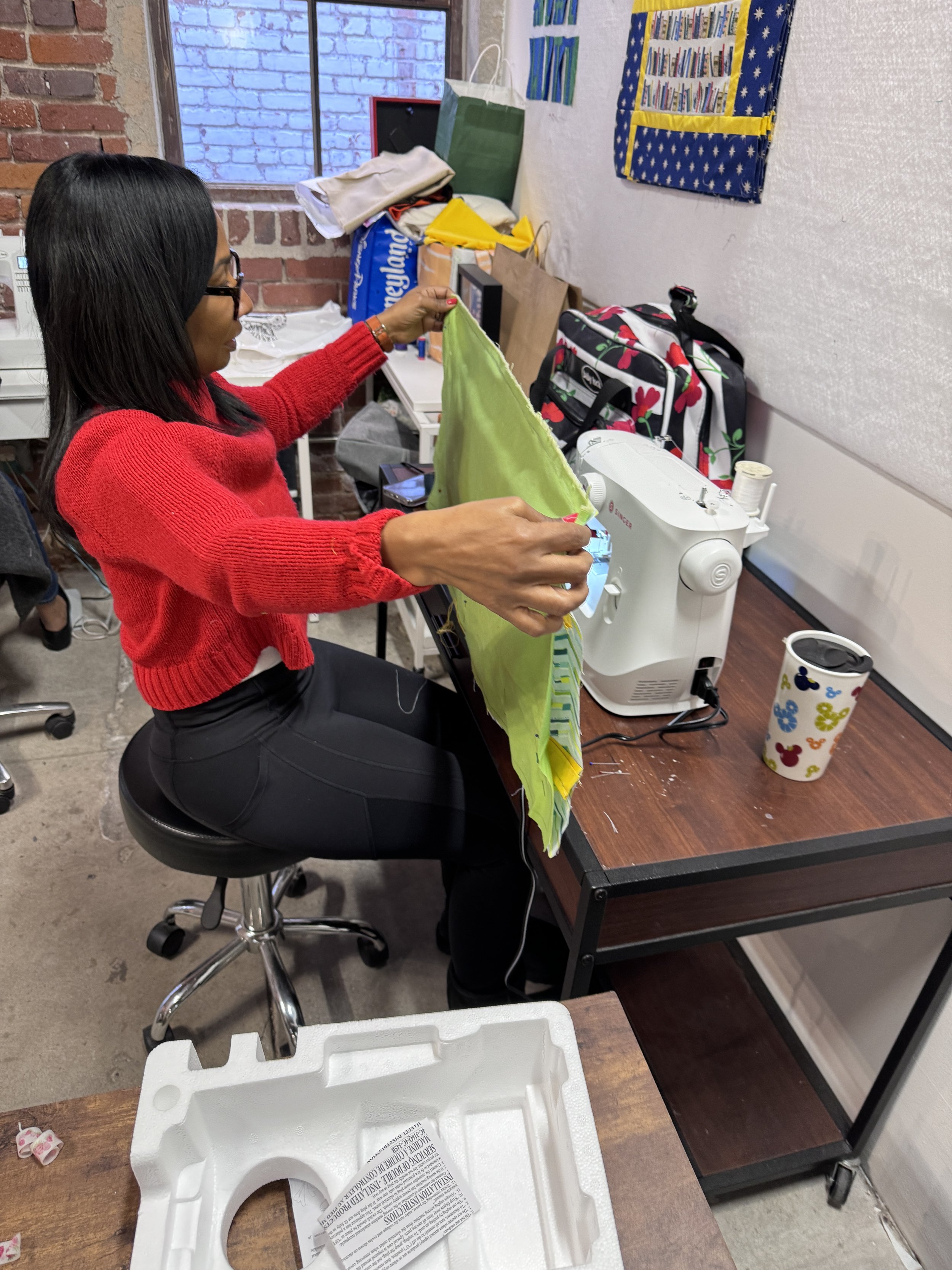 Woman sewing fabric using a sewing machine in charming sewing classroom.