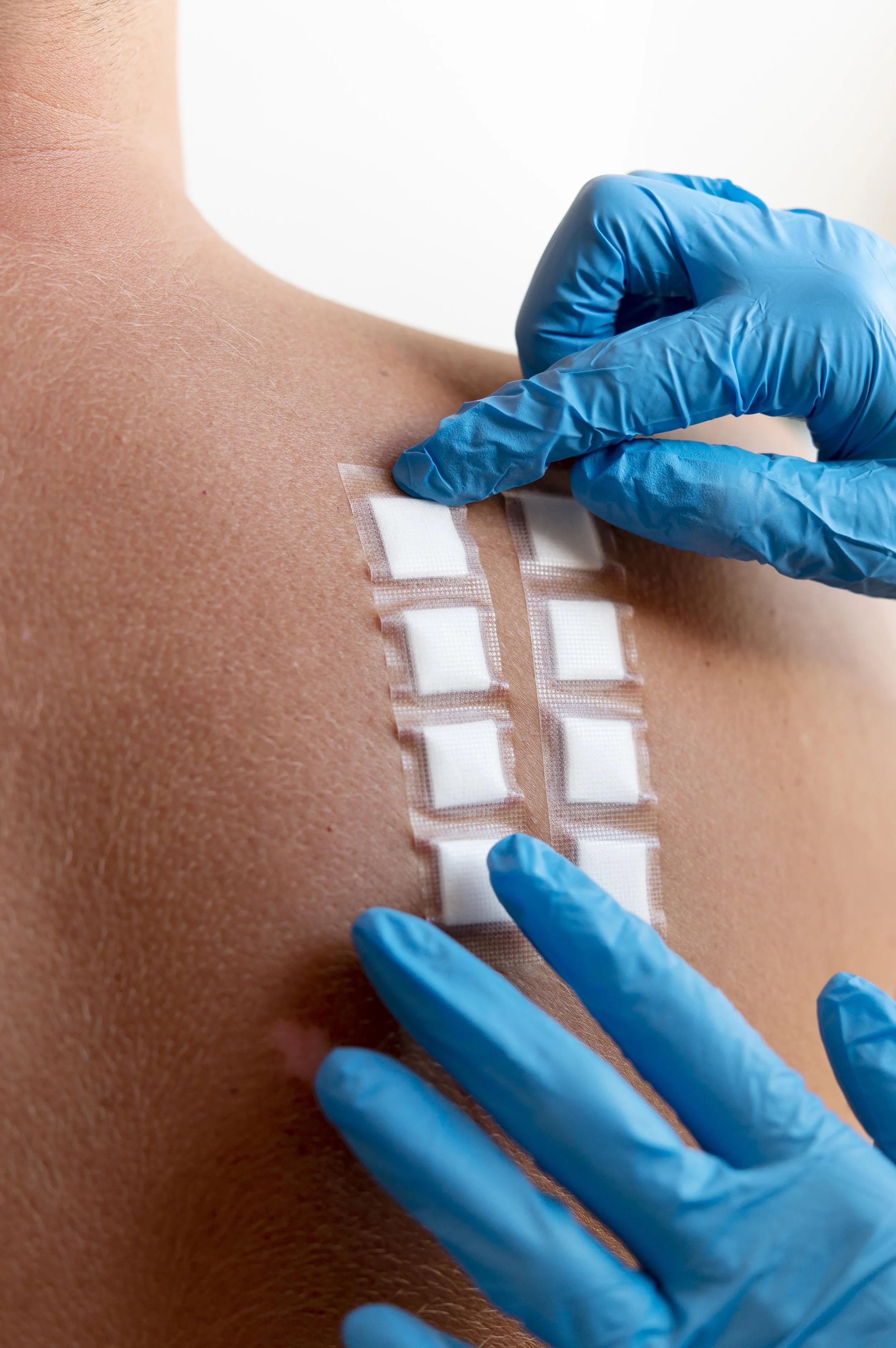 Close-up of a person receiving an injection in their upper arm, with a healthcare worker wearing blue gloves preparing to administer it.