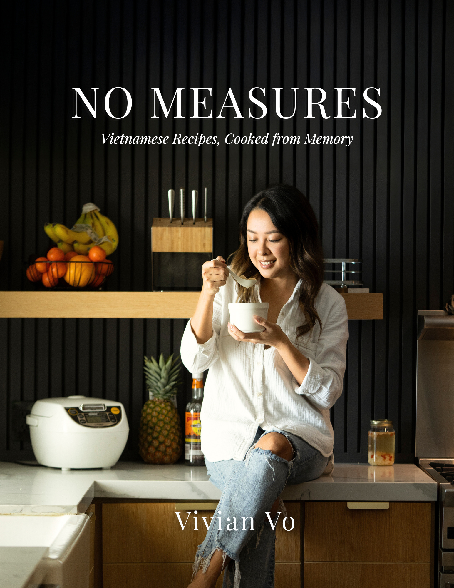 Book cover titled 'NO MEASURES' with the subtitle 'Vietnamese Recipes, Cooked from Memory', showing a woman sitting on a kitchen counter eating from a bowl, with fruits, a toaster, and a bottle in the background.