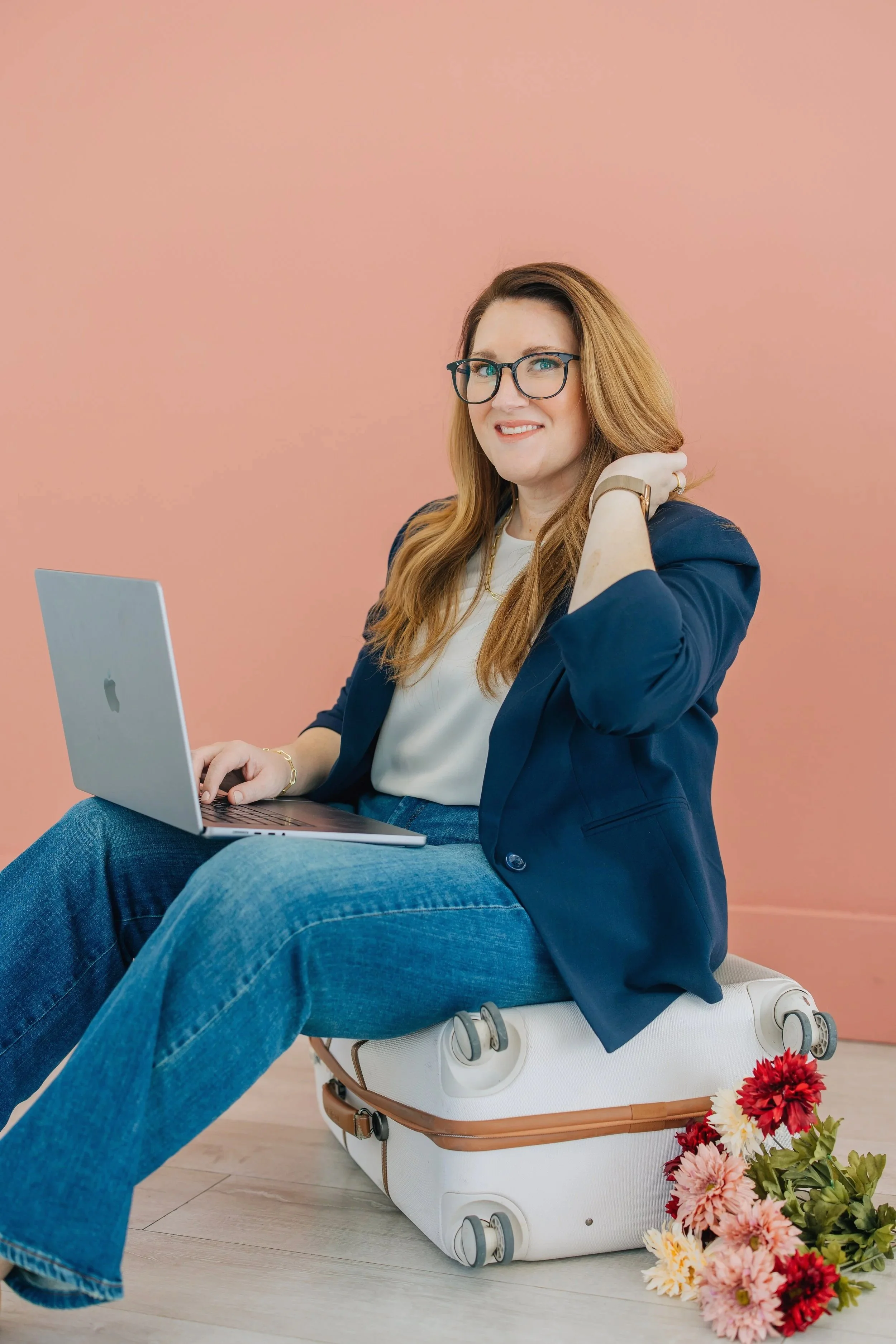 Amanda sits with laptop on her lap. She is looking at the camera while jostling her hair.