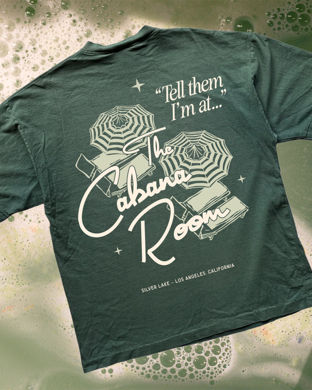 stylized flat lay mock up of a green garment dyed t-shirt with a custom motel-style design on the back