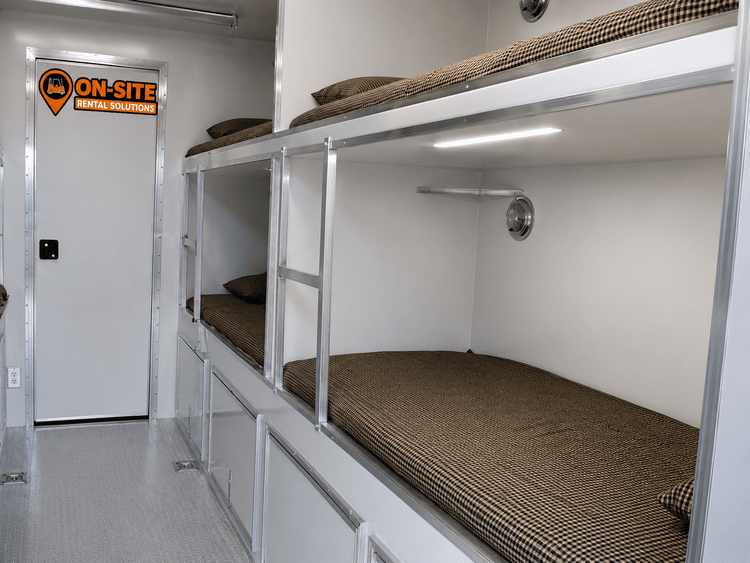 Bunkhouse trailer interior showing stacked bunks with individual reading lights and under-bunk storage drawers