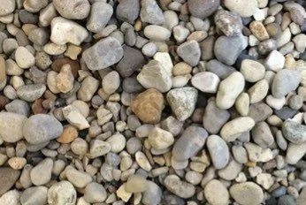 Close-up of small, smooth, multicolored pebbles on a gravel surface.