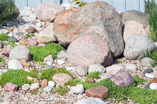 Decorative garden with large rocks, small pebbles, and green plants.