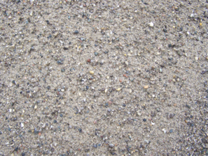 Close-up of sandy ground with small pebbles and grains.