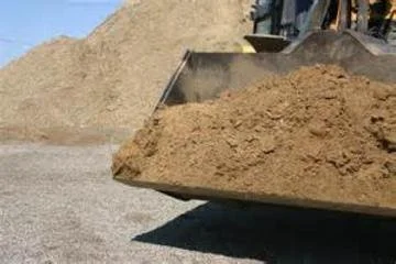 Close-up of a construction site with a large pile of dirt in a machine bucket.
