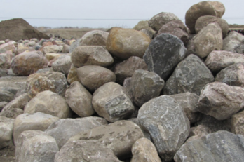 A pile of large, rounded rocks on a beach or shoreline