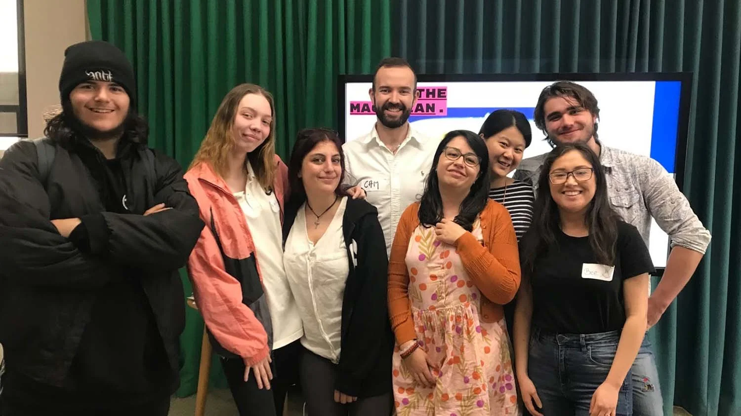 Eight people from the Oasis team and program participants are gathered together, smiling at the camera.