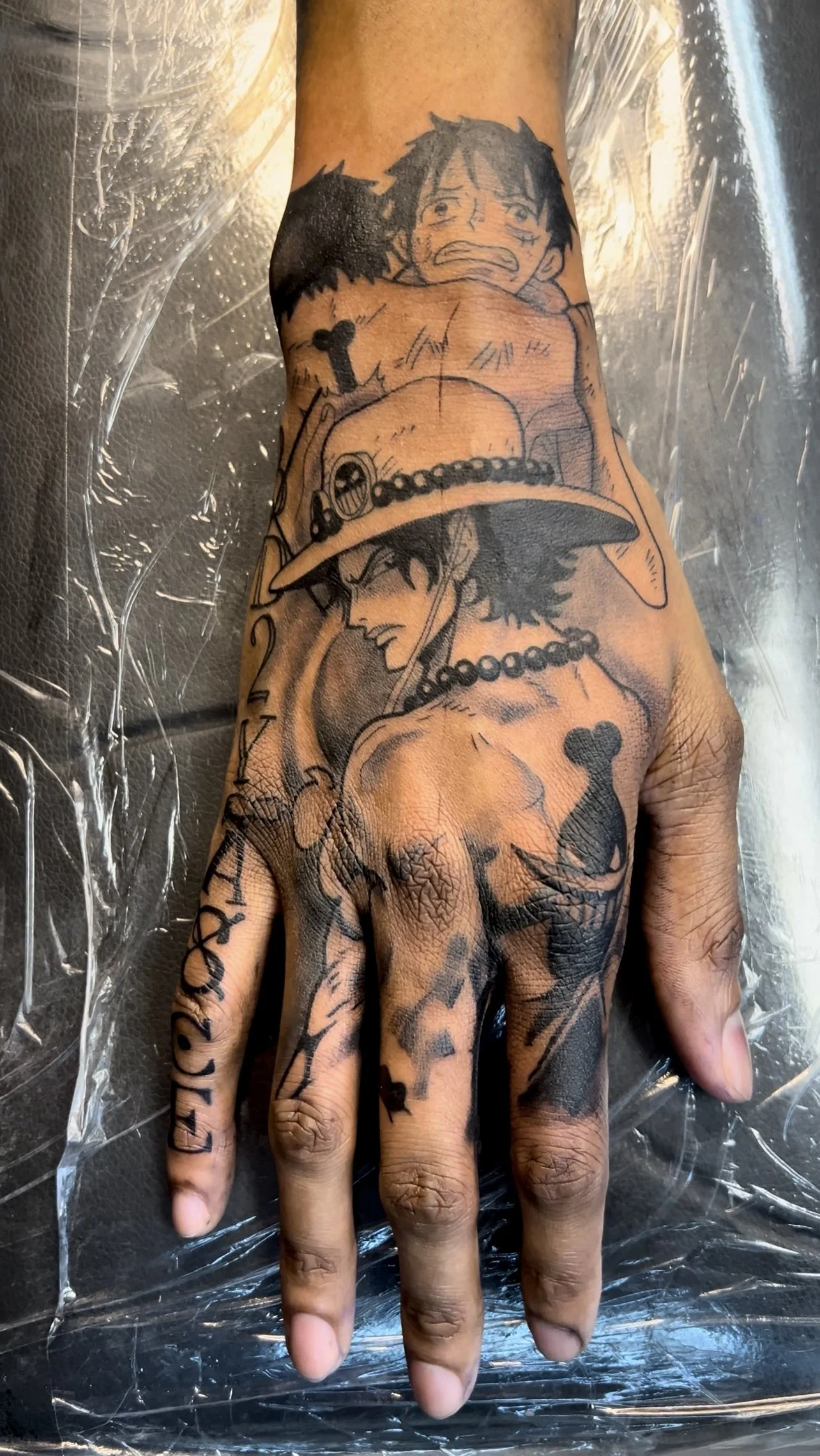 Tattooed hand with characters from the anime One Piece, including Luffy and Ace.