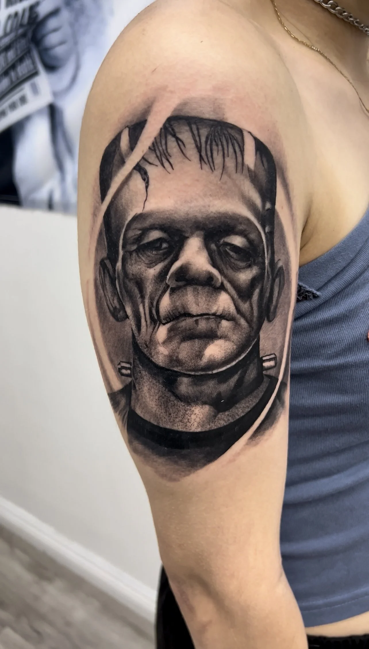 Black and gray realistic tattoo of a man's face on upper arm, with detailed facial features and expression.