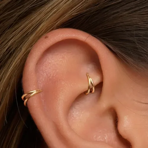 Close-up of a person's ear with two gold hoop earrings.