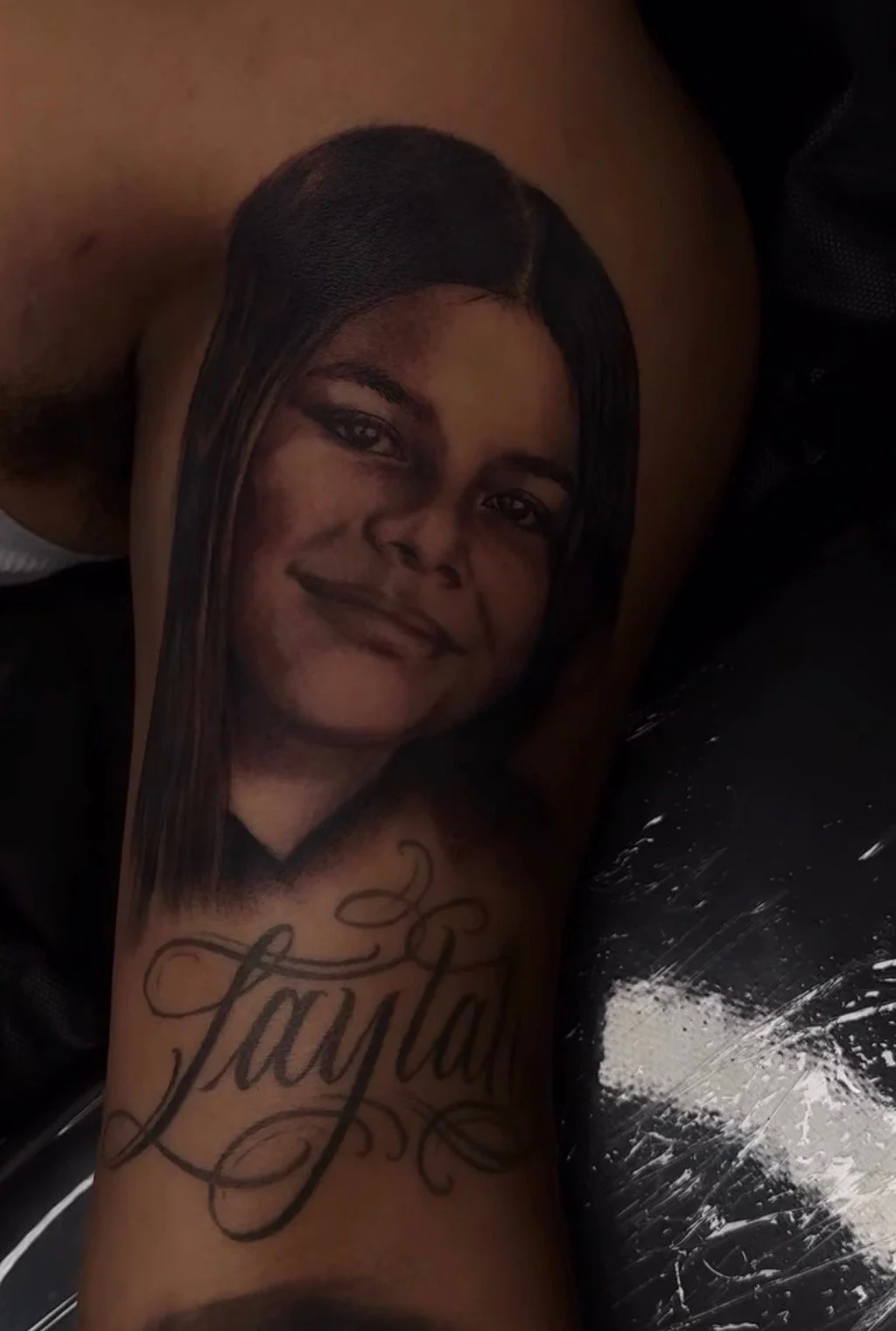 Tattoo of a woman's face on a person's arm, with the word 'Layla' written in cursive below the face.