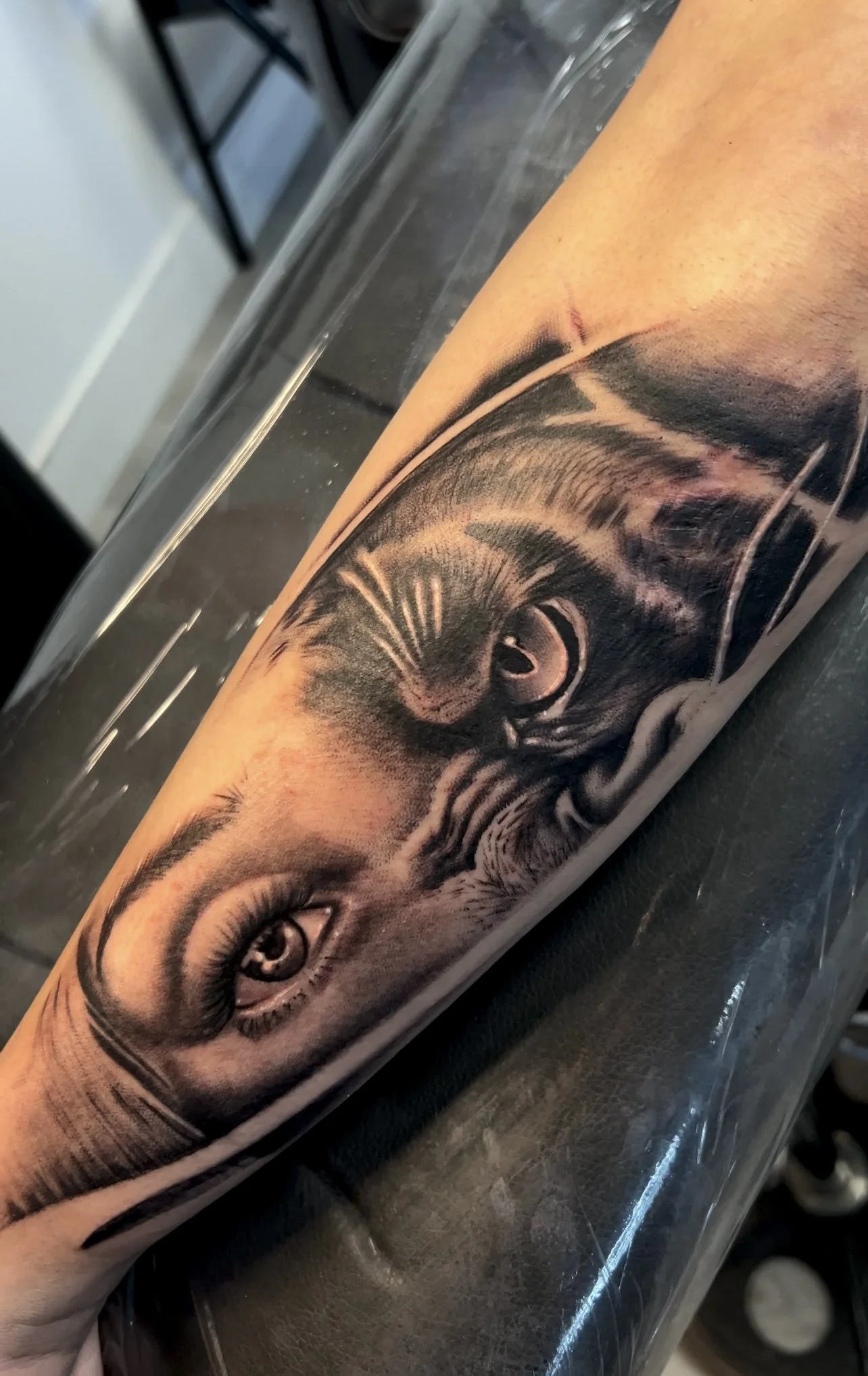 A black and gray tattoo of a woman's eye and a cat's eye, with detailed shading and realistic features.
