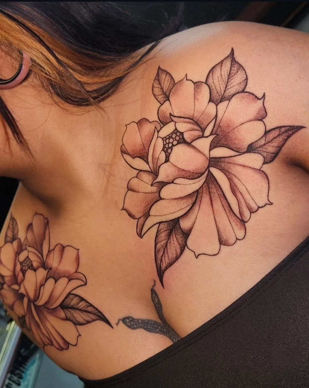 A tattoo of large, detailed flowers on a person's shoulder and upper chest.