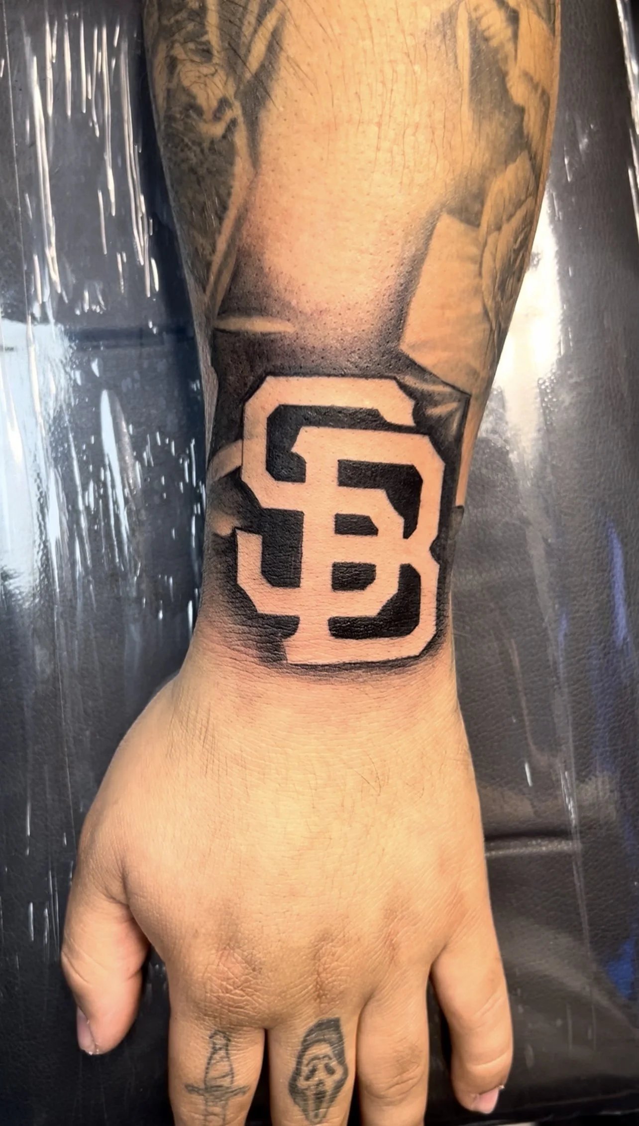A tattoo of the San Francisco Giants logo on a person's inner forearm.