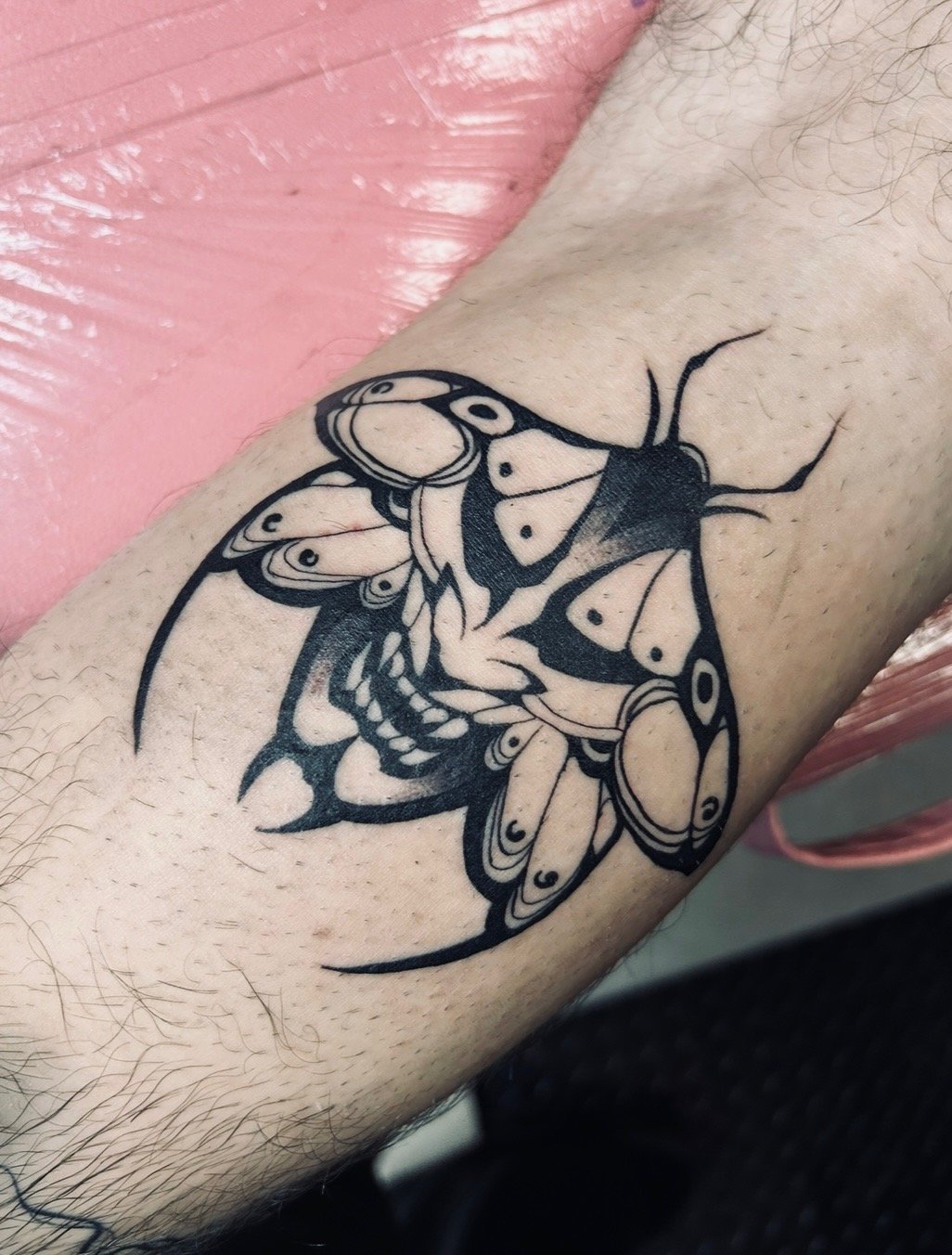 Black tattoo of a butterfly on a person's arm.