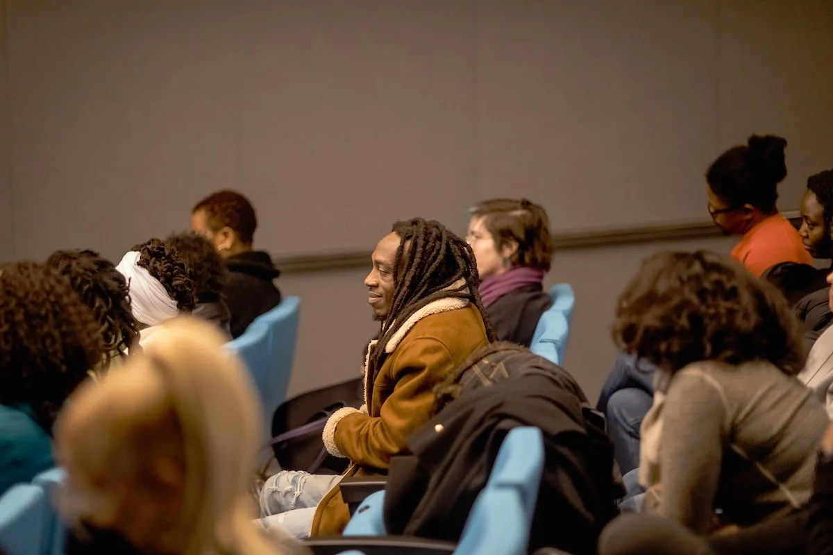 People seated in a conference room listening to a presentation or speaker.