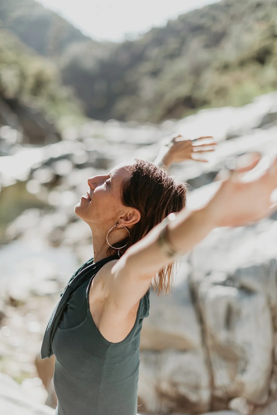 Chandra, holistic vitality coach, spreading her arms and smiling towards the sun