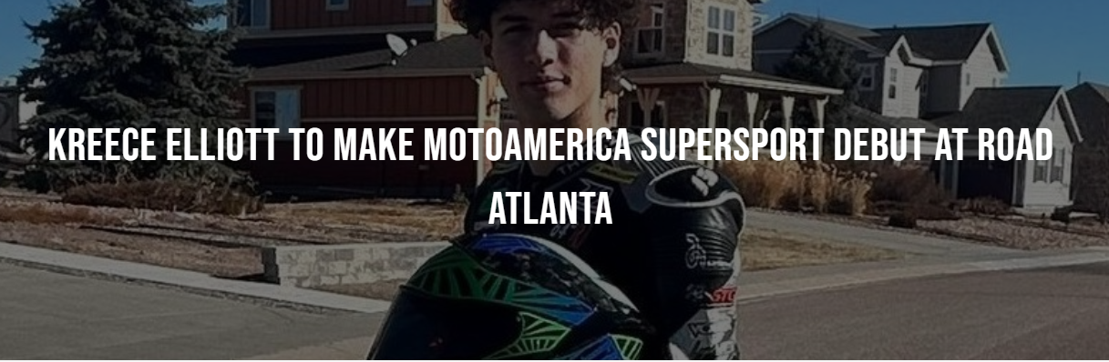 A young man holding a motorcycle helmet, standing on a street in front of residential houses on a sunny day.