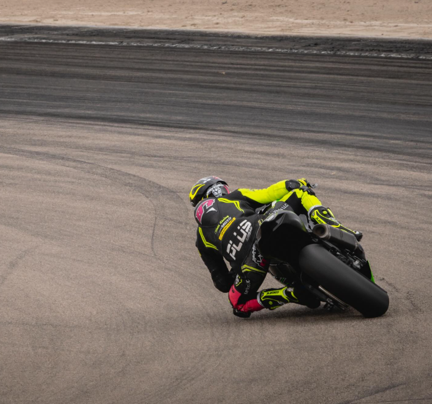 Motorcycle racer in yellow and black suit leaning into a turn on a racetrack.