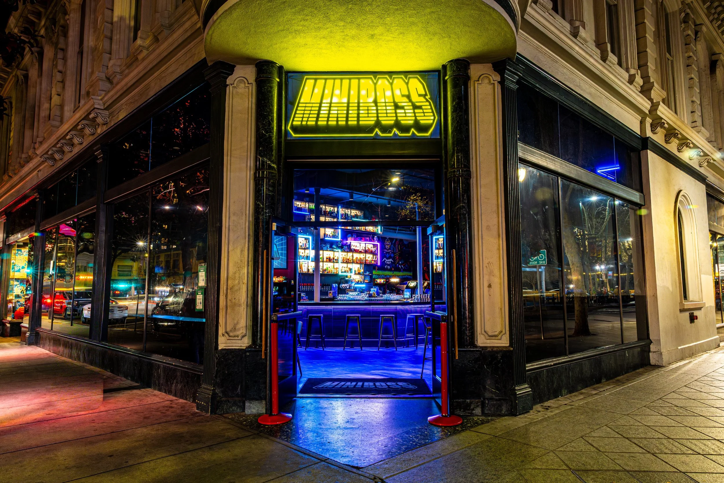 Neon sign reading 'WINDOSS' above the entrance of a bar or nightclub on a city street at night.