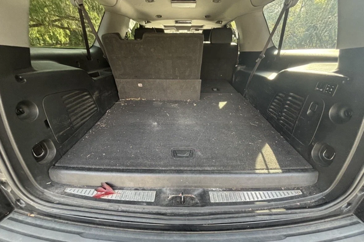 The trunk of an SUV with the rear seats folded down, showing a mostly empty cargo area with some dirt and debris.