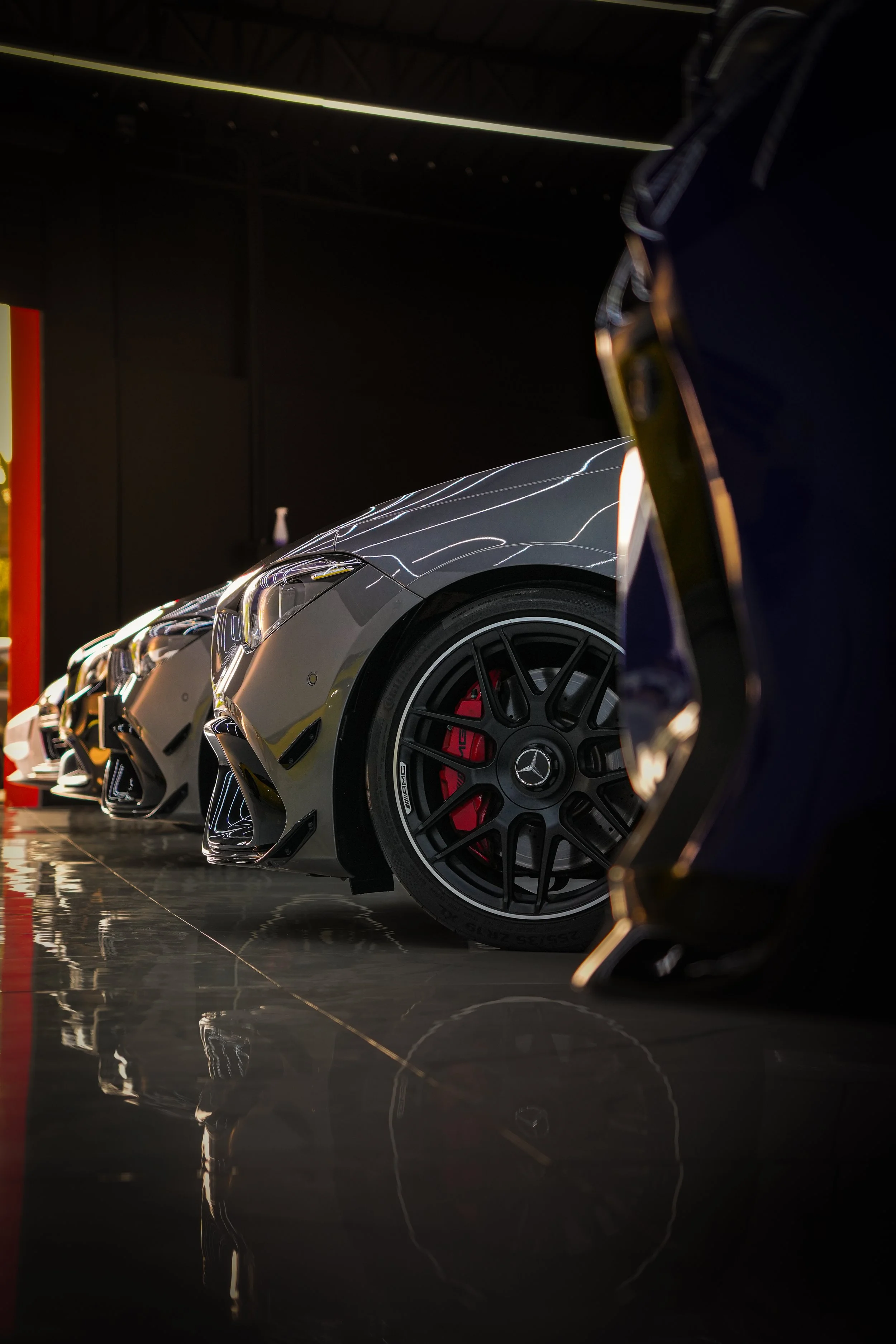 Line of luxury sports cars on display in a showroom, with reflections on the polished floor.
