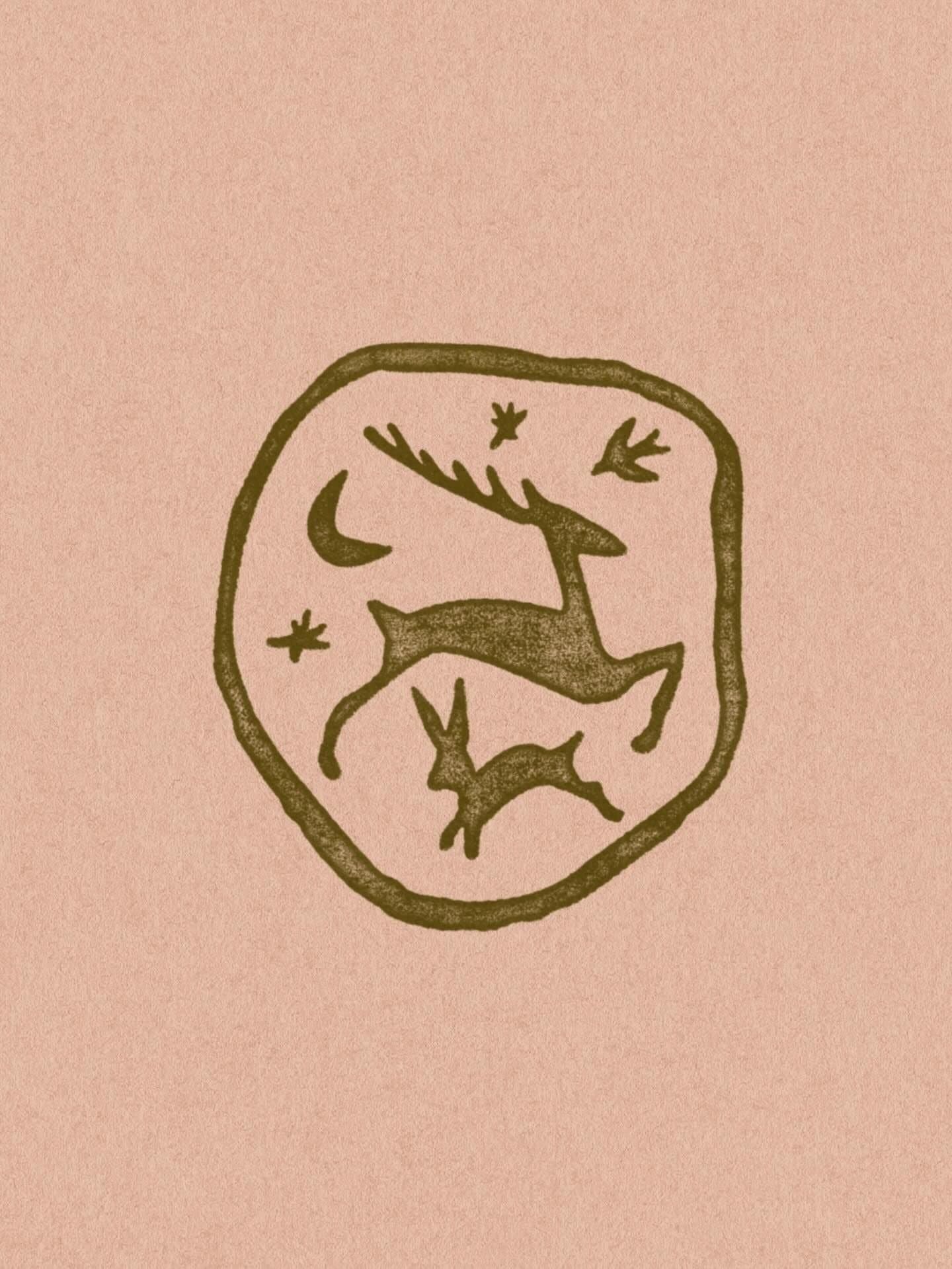A drawing of a reindeer with antlers inside a circular outline, with stars and a crescent moon around it.
