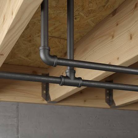 Interior view of plumbing pipes installed under a wooden floor in a construction or renovation setting