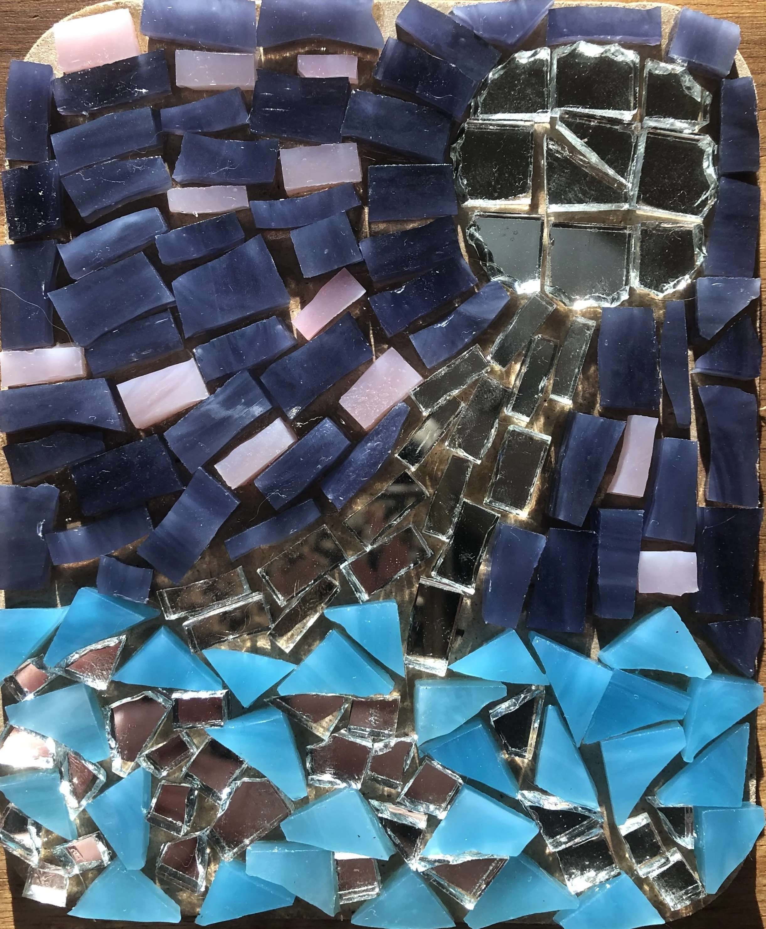 Small mosaic of a moon and moonbeams shining on the ocean