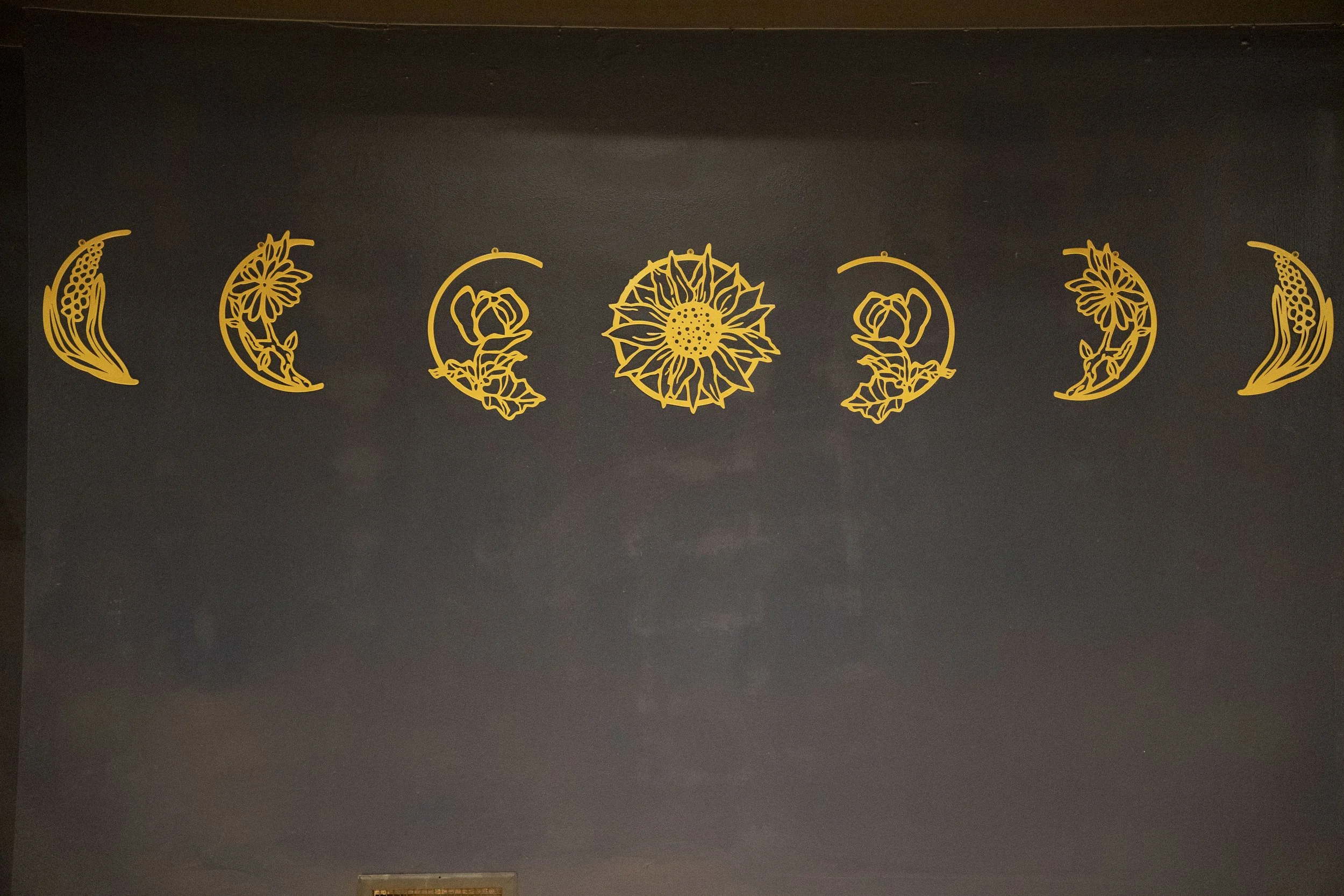 Decorative yellow floral and moon designs on a dark wall.