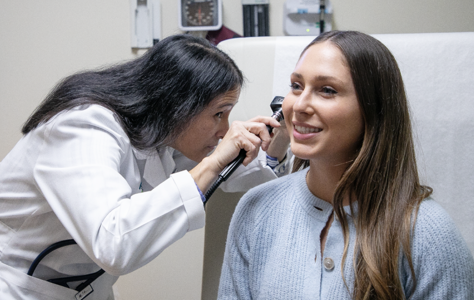 A female doctor examining a woman's ear with an otoscope in a clinic.